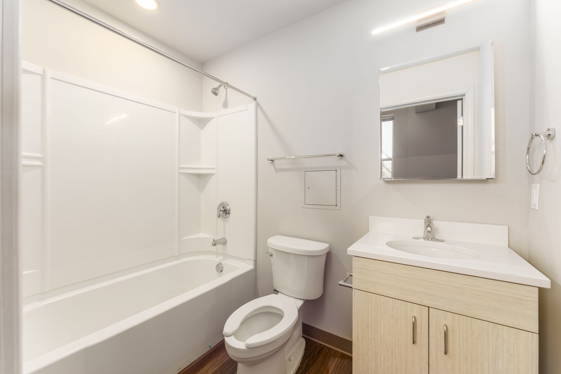 A bathroom with a toilet , sink , bathtub and mirror.