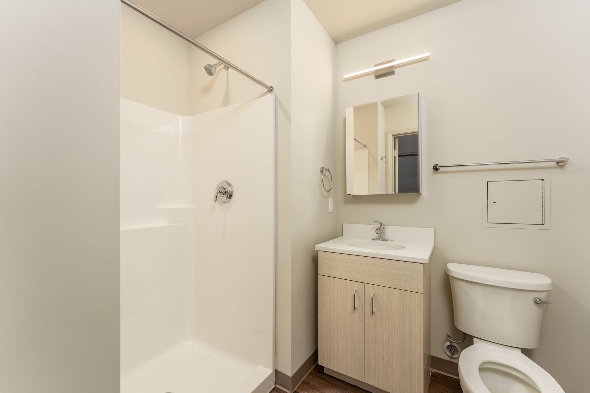 A bathroom with a toilet , sink , shower and mirror.