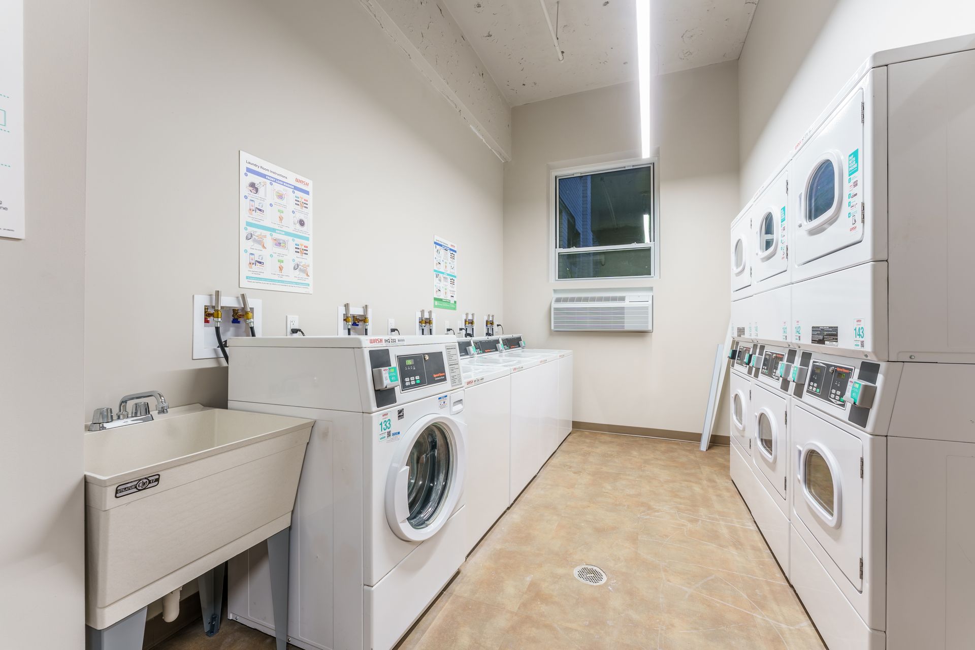 A laundromat with a sink , washers and dryers.