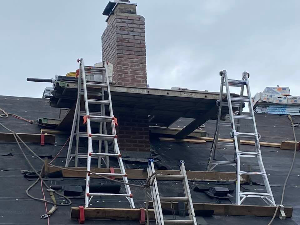 Rooftop with ladders, chimney, and wooden scaffolding. Construction work on a roof.
