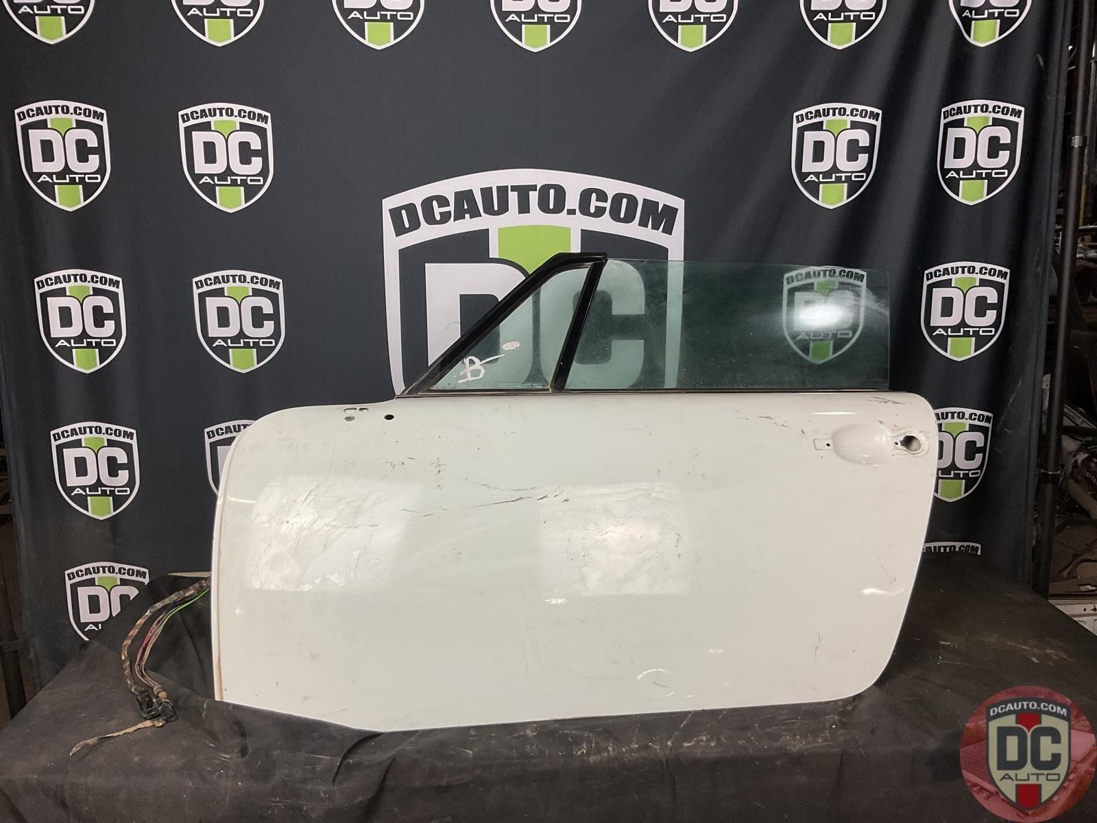 A white door is sitting in front of a dcauto.com banner
