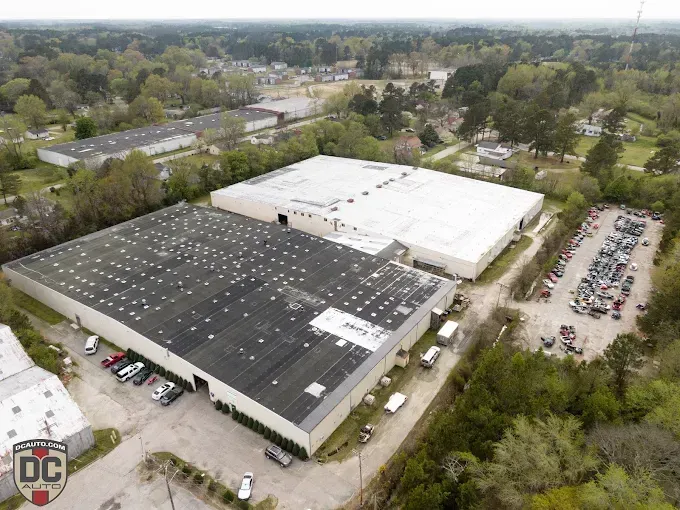 An aerial view of a warehouse with a lot of cars parked in front of it