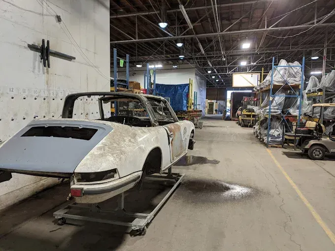 A white car is sitting on a lift in a warehouse.