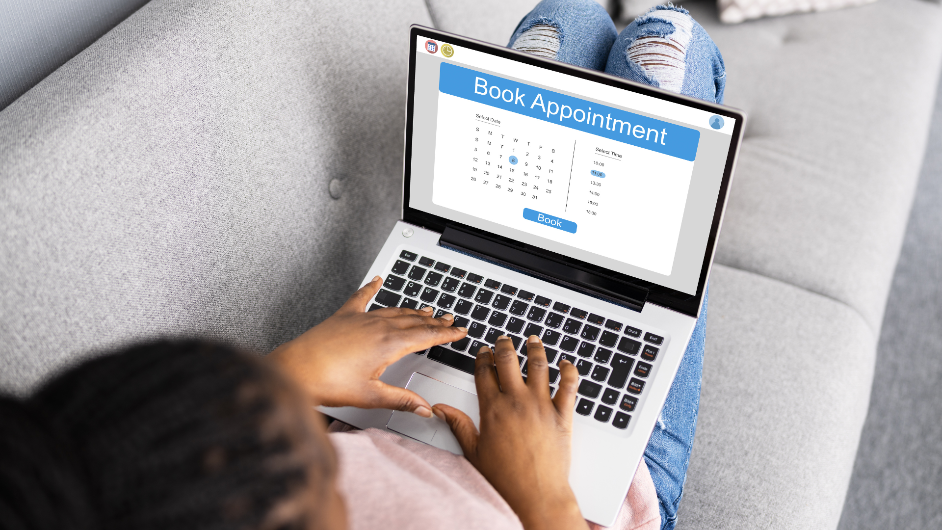 Person on couch using a laptop to book an appointment online; calendar displayed.