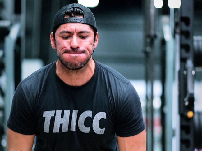 a man wearing a black t-shirt with the word thicc on it .