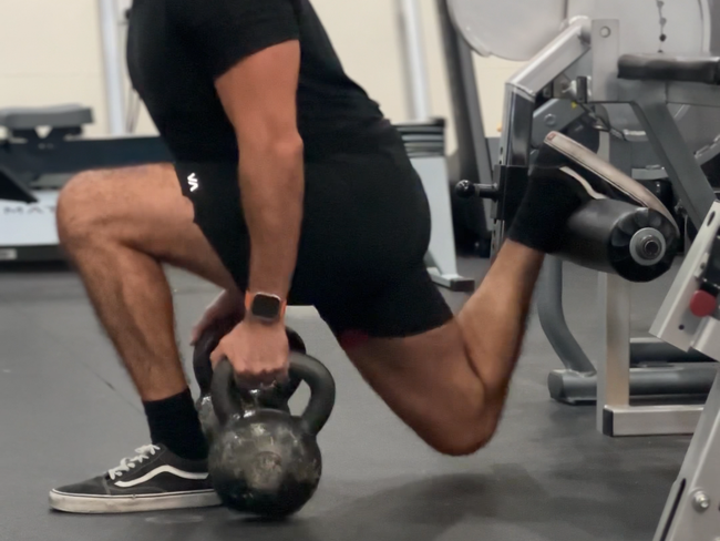 a man squatting down holding a kettlebell in a gym