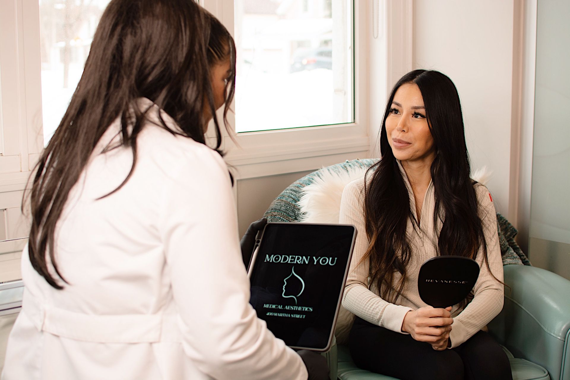 A woman is sitting in a chair talking to another woman.