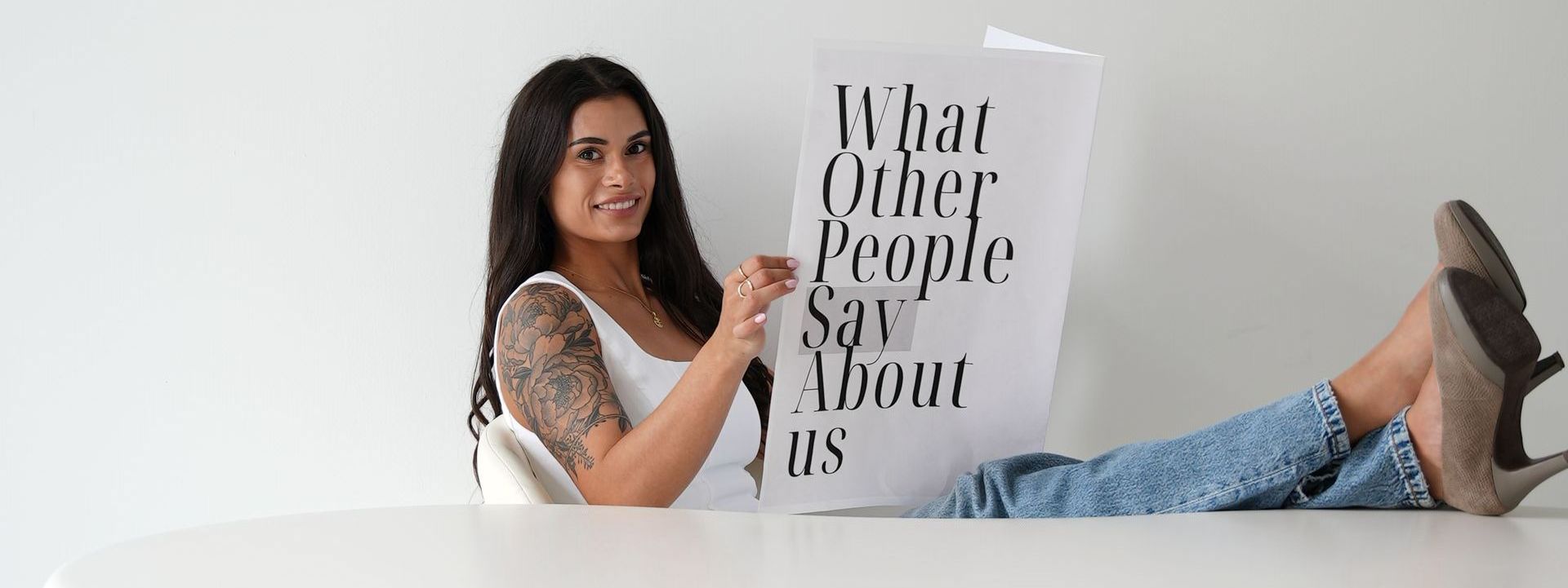 A woman is laying on a table holding a sign that says what other people say about us.