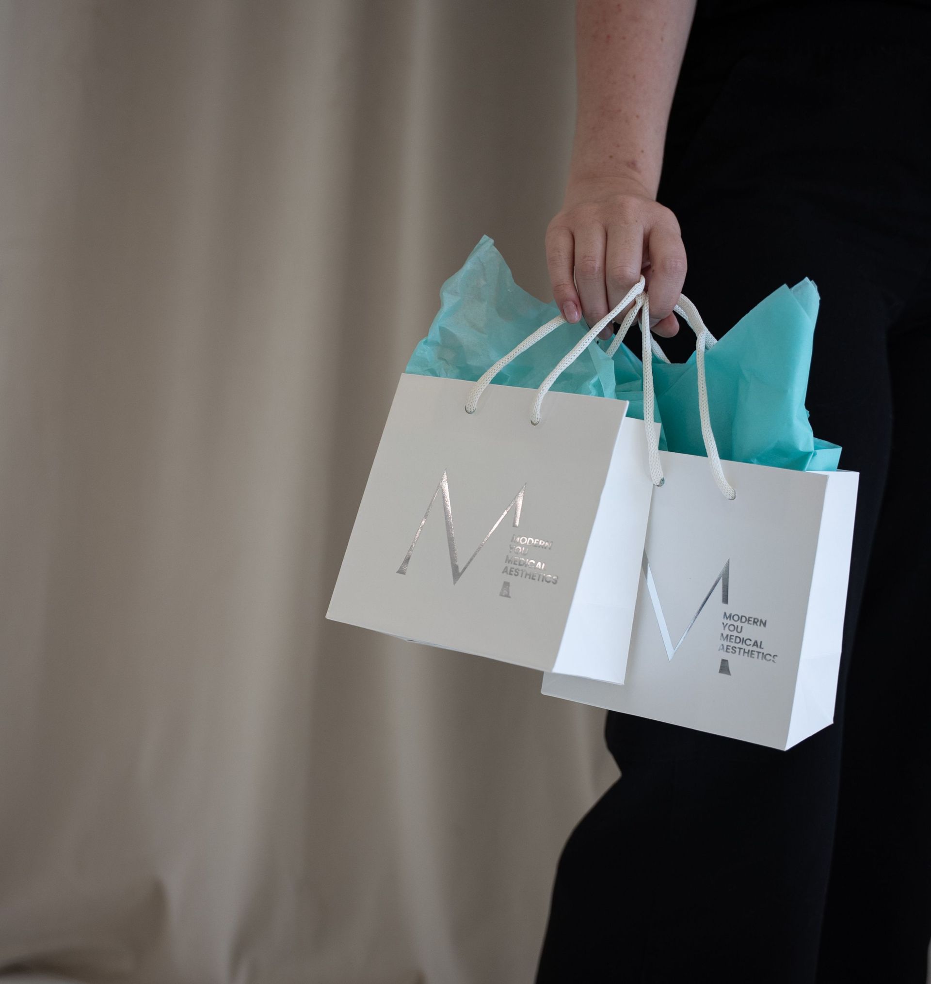 Waiting room with teal furniture, chandelier, and a white cabinet with blue bottles.