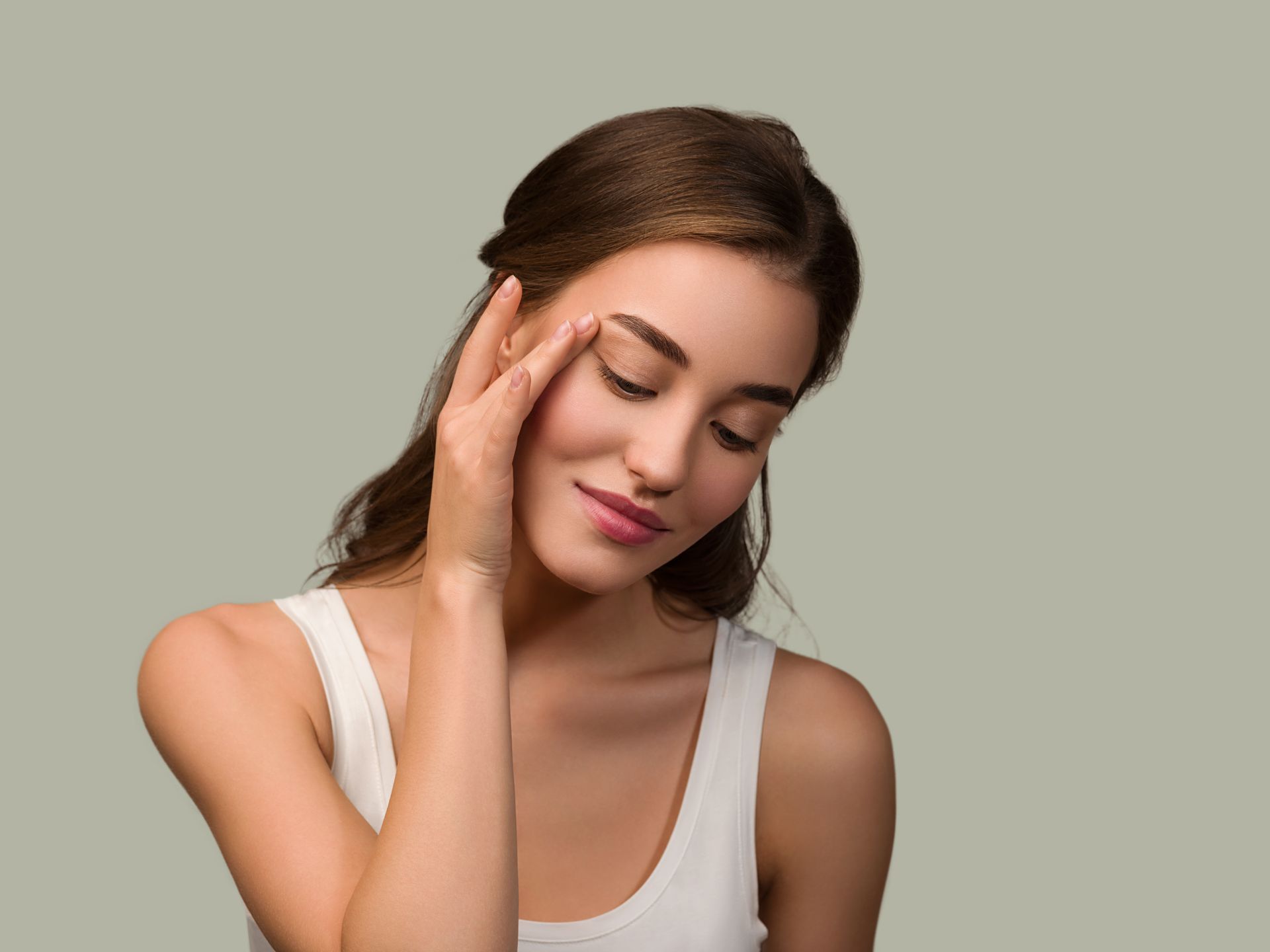 A woman is touching her face with her hand and smiling.