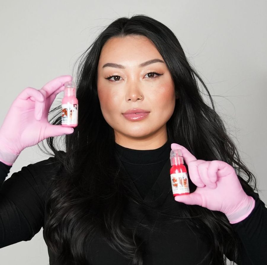 Woman in gloves holding up bottles of pink and red liquid.
