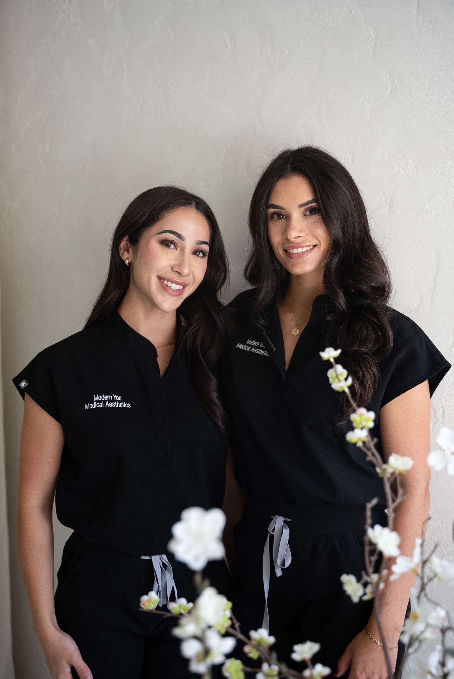 Woman receiving a facial treatment. Aesthetician in pink gloves holds device to client's face in a white-walled room.