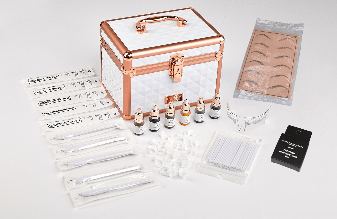 Rose gold and white cosmetic case with eyebrow microblading supplies.