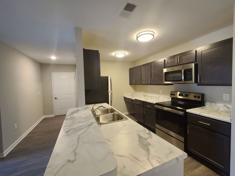 A kitchen with a sink , stove , microwave and dishwasher.