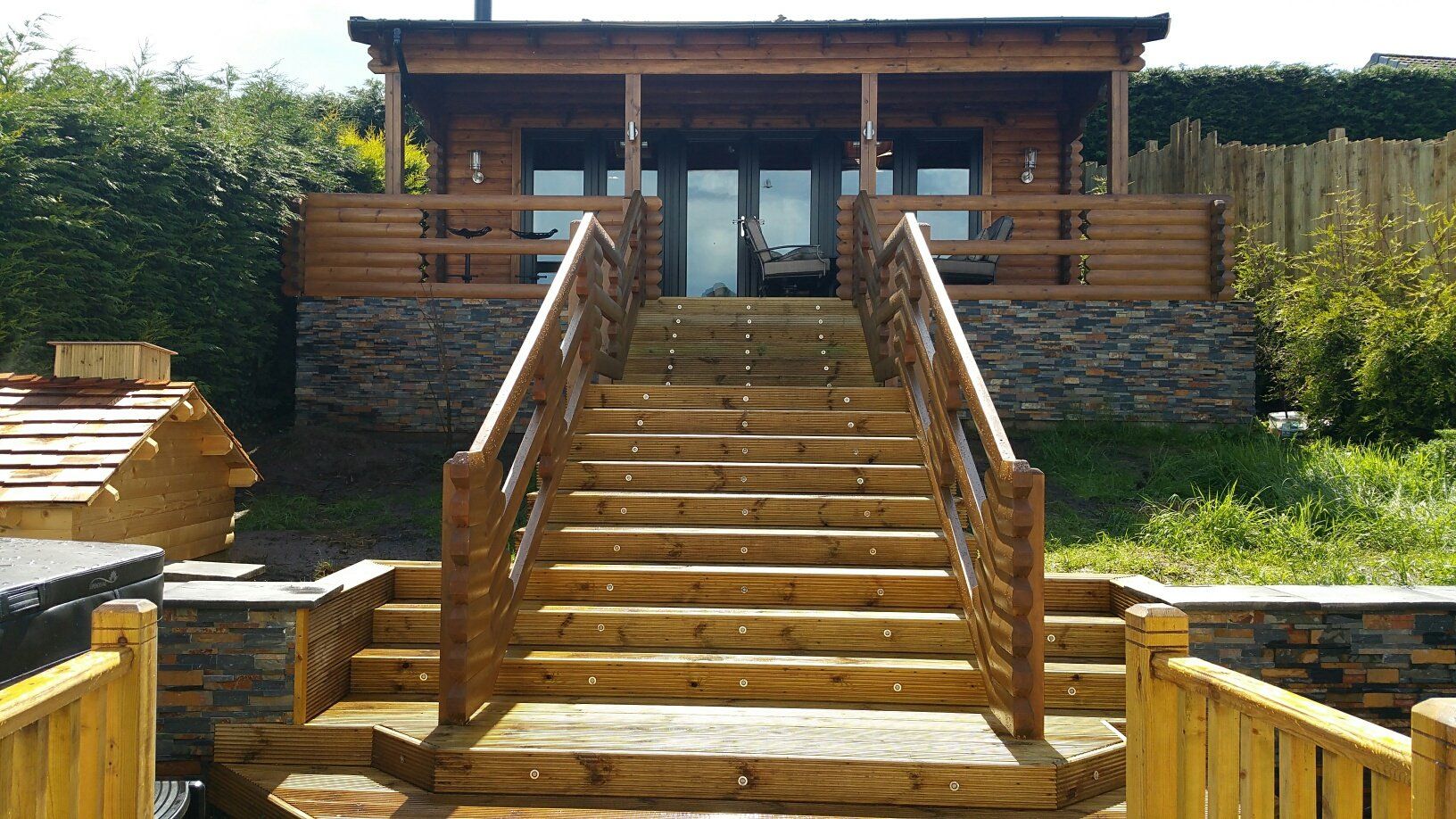 Drewniana chatka ze schodami prowadzącymi na górę; stopnie mają wbudowane oświetlenie i poręcze po obu stronach.