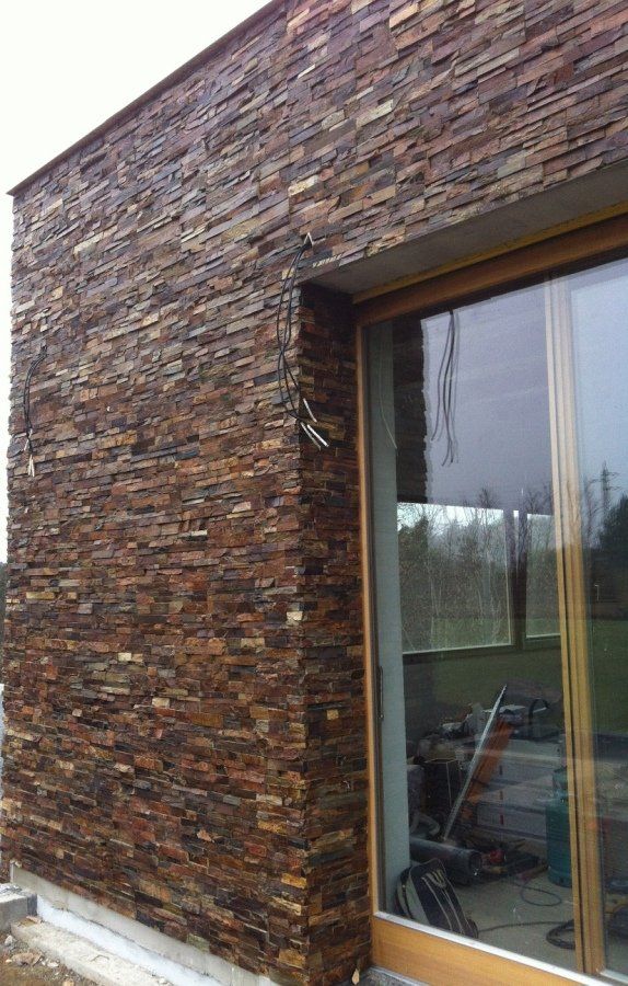 Zewnętrzna część budynku z okładziną z brązowego kamienia obok dużego okna.