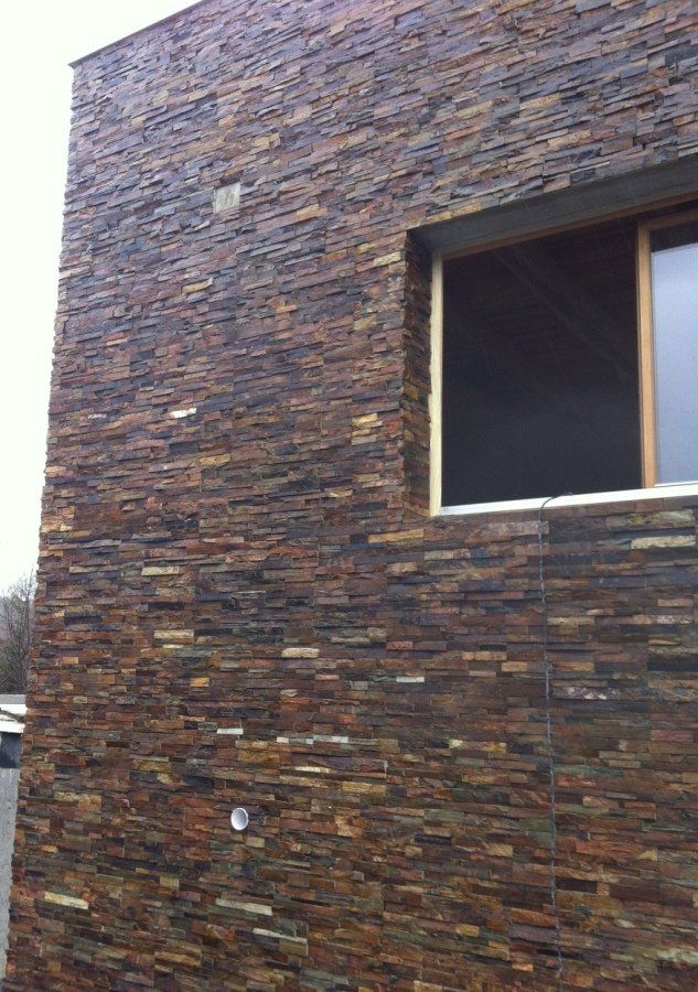 Zewnętrzna część budynku z ciemną kamienną płytką i oknem.