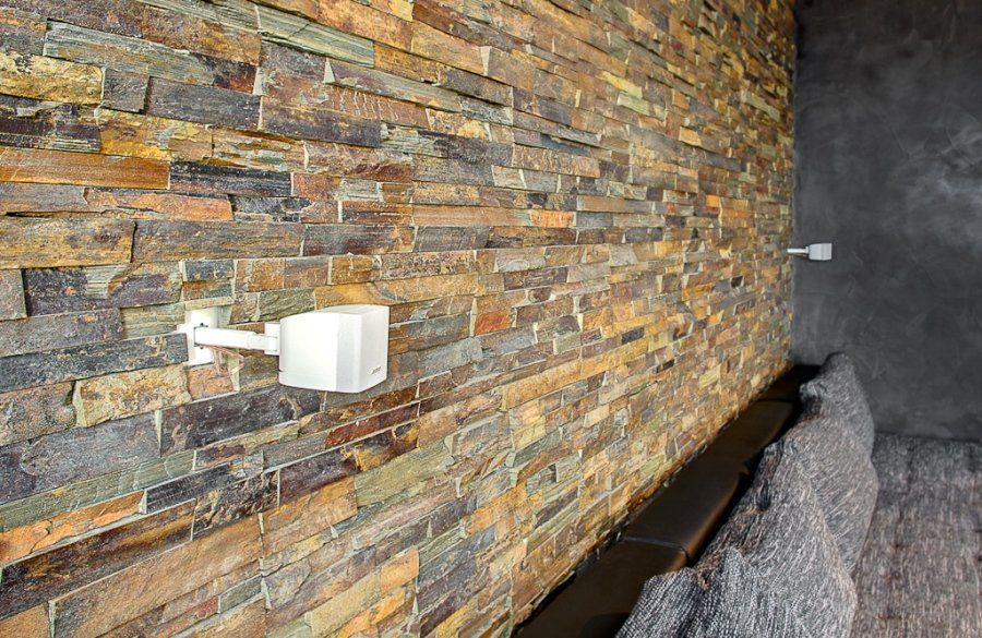 Kamienny mur z zamontowanymi na biało kamerami bezpieczeństwa.