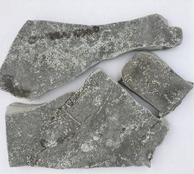 Szare, połamane fragmenty skały na białym tle.