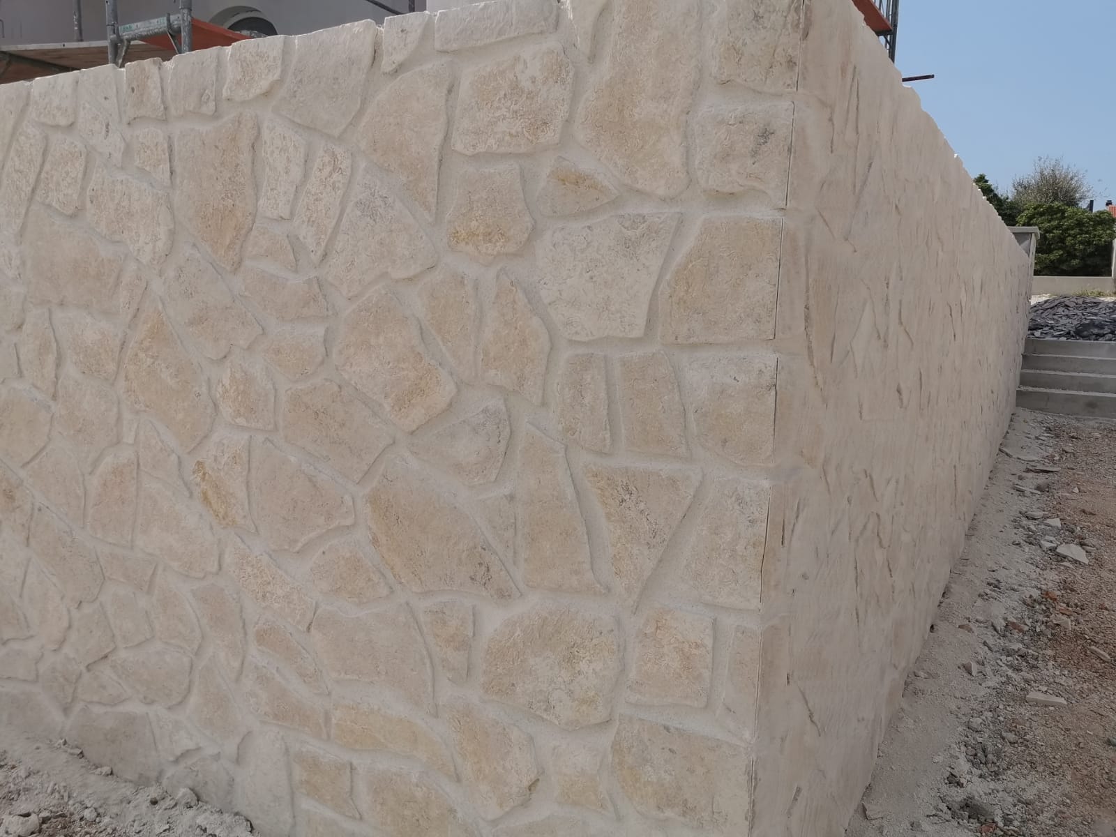 Mur kamienny z szorstkimi, jasnymi kamieniami, zakrzywiony i pełen zakrętów.