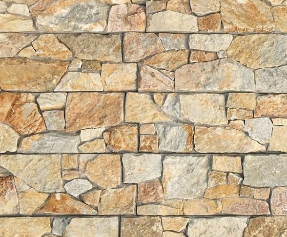 Zbliżenie na kamienny mur. Nieregularne kamienie w kolorze jasnobrązowym, szarym i brązowym są ściśle do siebie dopasowane.