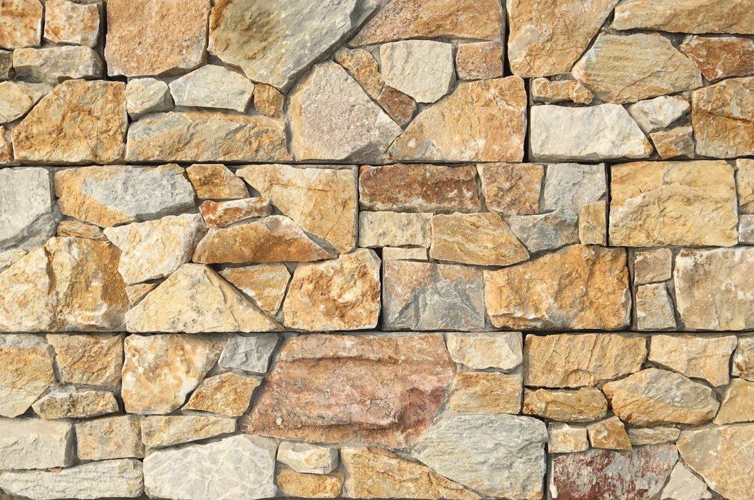 Brązowo-złoty kamienny mur o różnych kształtach i rozmiarach, ułożony poziomo.