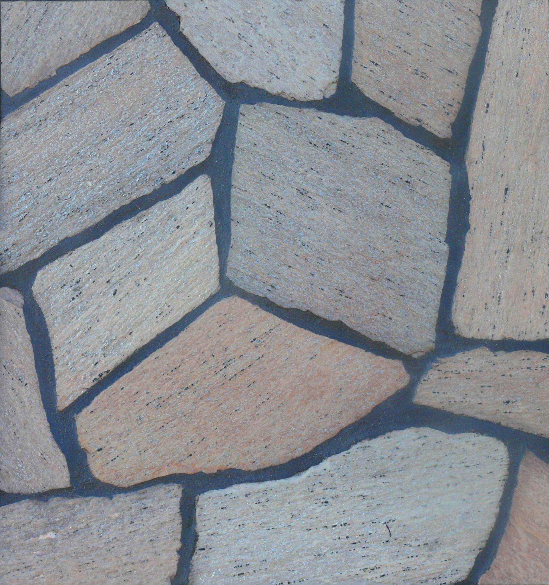 Płytki kamienne o nieregularnych kształtach w odcieniach beżu, szarości i brązu, oddzielone ciemnoszarą fugą.