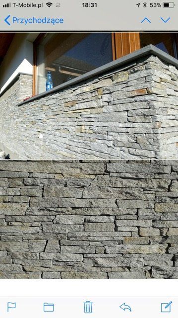 Kamienna okładzina ścienna na zewnątrz budynku. Szare i brązowe kamienie z ciemną czapką.