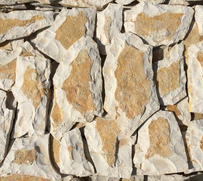 Okładzina ścienna z kamienia z kremowymi i jasnobrązowymi elementami o nieregularnych kształtach.