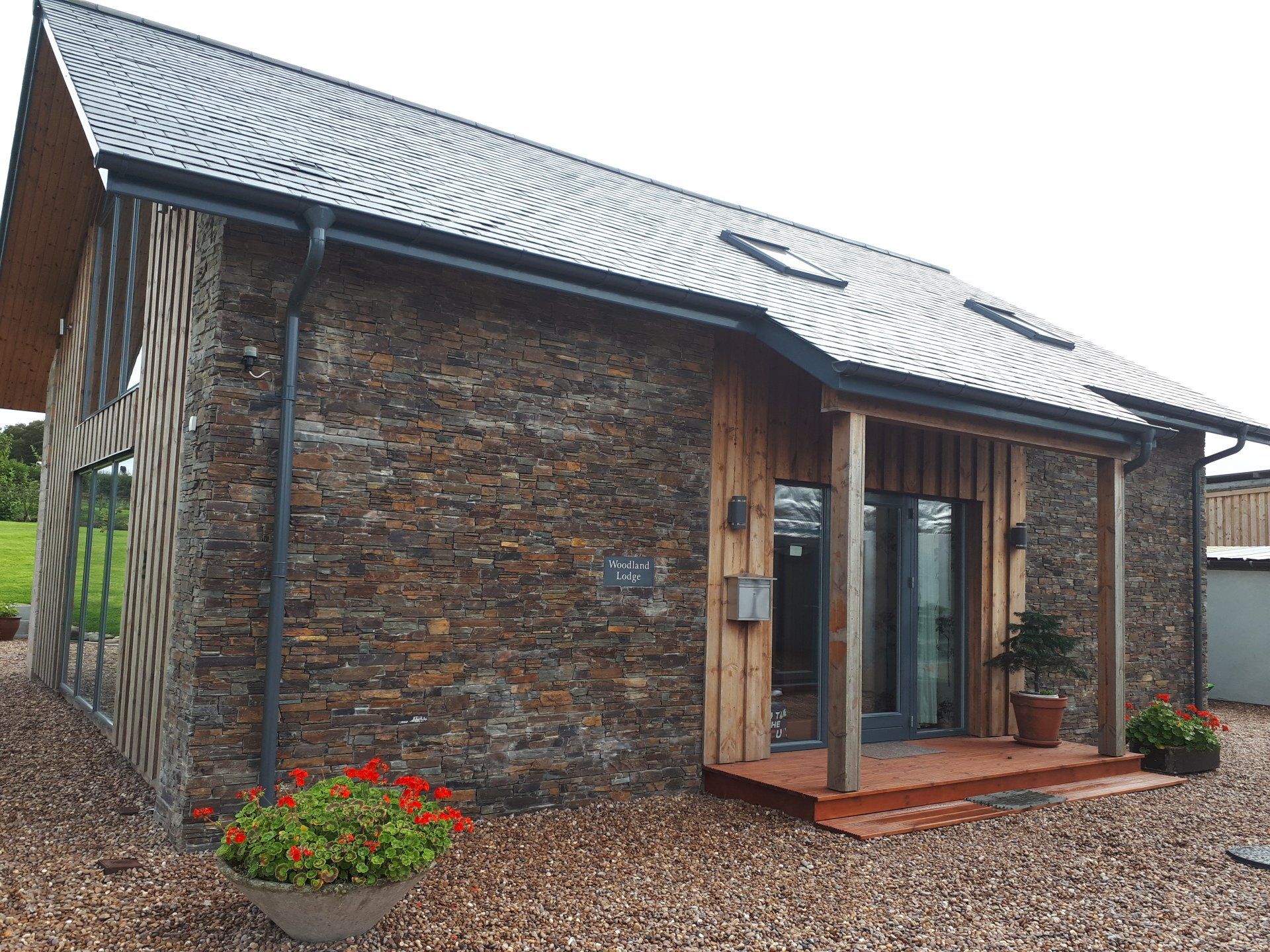 Mały kamienny dom z łupkowym dachem i werandą.