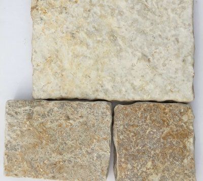 Trzy jasne, prostokątne płytki kamienne ułożone na białym tle. Mają chropowatą, teksturowaną powierzchnię.