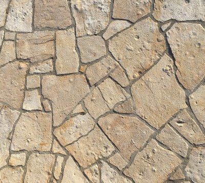 Płytki kamienne w kolorze jasnobrązowym o nieregularnym wzorze z ciemnoszarą fugą.