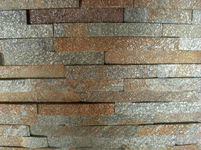 Teksturowana ściana z poziomymi, prostokątnymi kamieniami w odcieniach brązu, szarości i czerwieni.