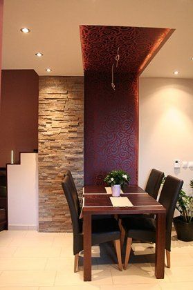 Jadalnia ze stołem z ciemnego drewna, czterema krzesłami i ścianą z kamienia z wzorzystą tapetą.