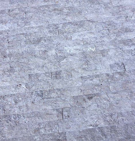 Szary kamienny mur, składający się z prostokątnych bloków o zróżnicowanej fakturze.