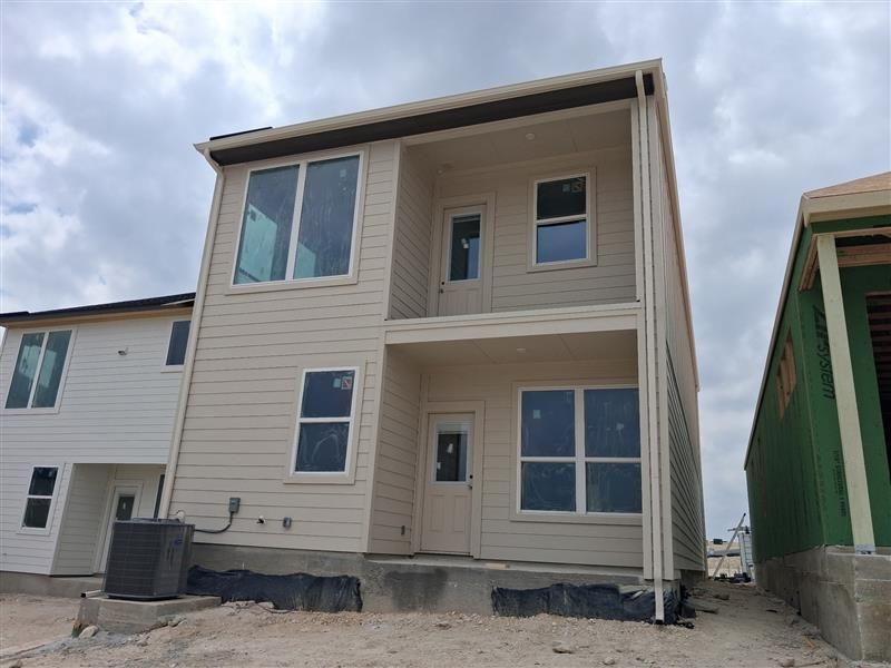 Newly built beige two-story house with large windows under a cloudy sky