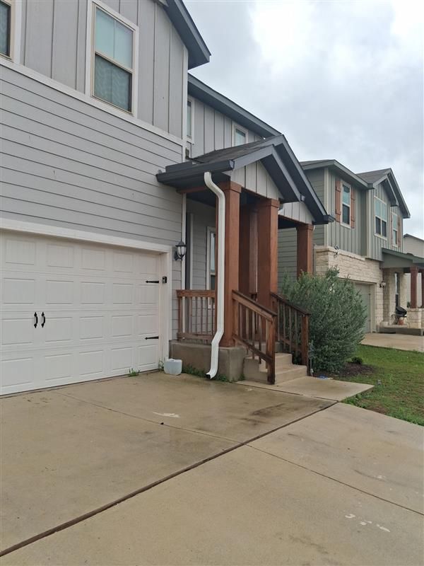 Suburban townhouse entry with garage, front steps, and concrete driveway.
