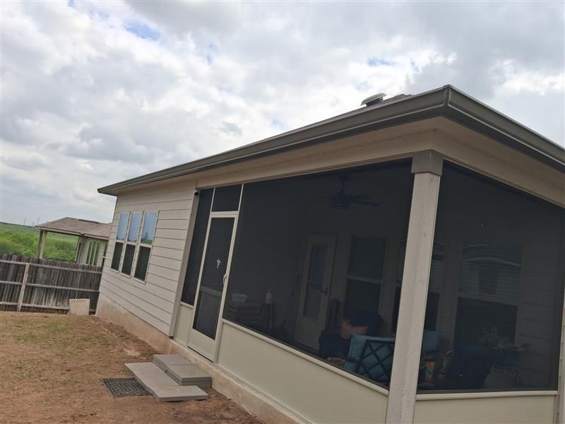 Covered porch on a beige house with screen walls and a cloudy sky.