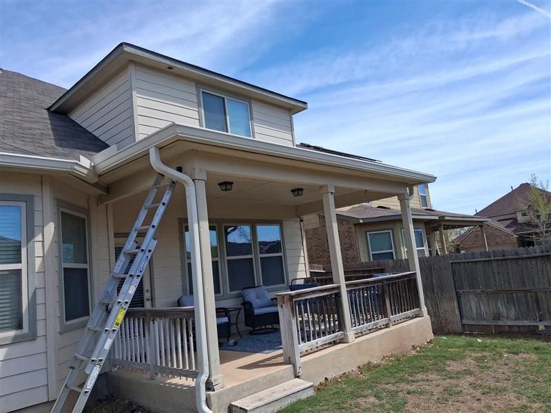 House with covered backyard patio and ladder leaning against the roof