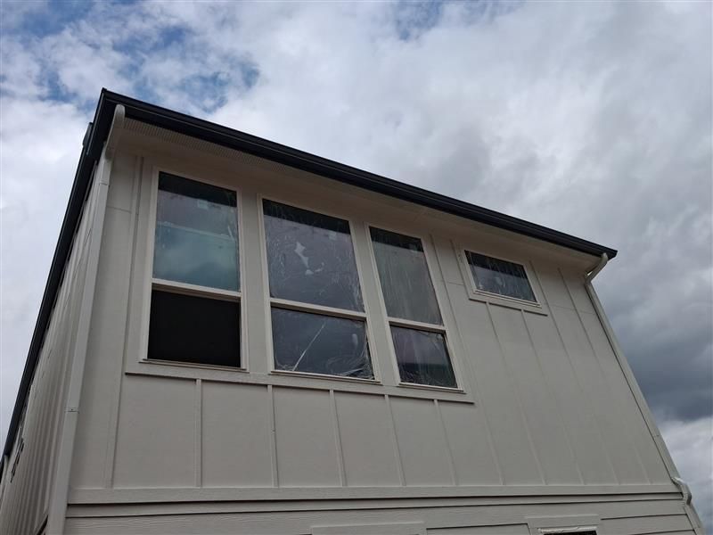 Exterior of a house with white siding and large windows under a cloudy sky