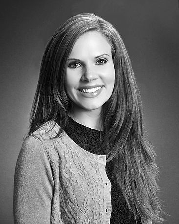 A woman with long hair is smiling in a black and white photo.