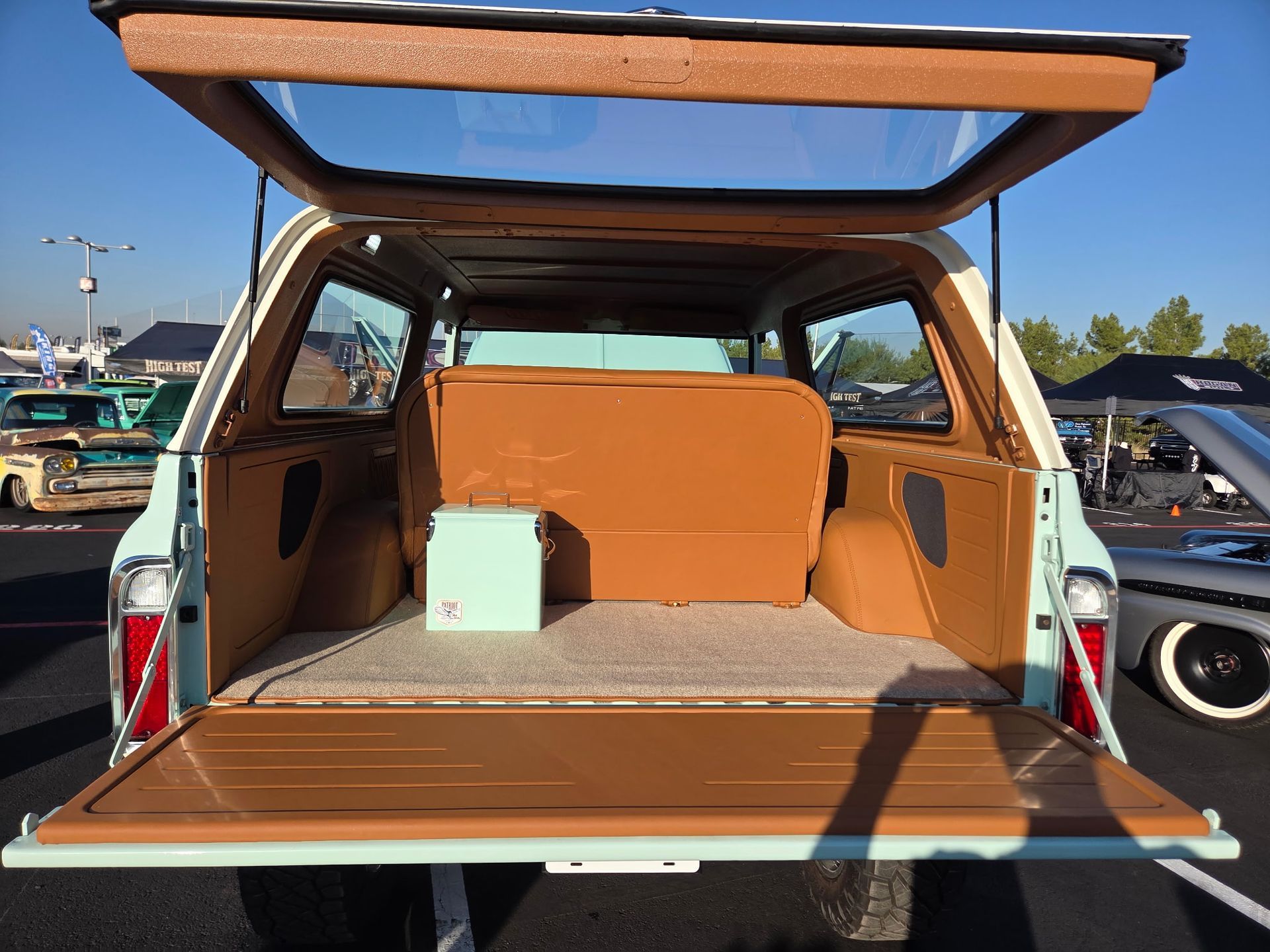 Open rear of a light blue and brown classic SUV, revealing a brown interior and a light blue box.
