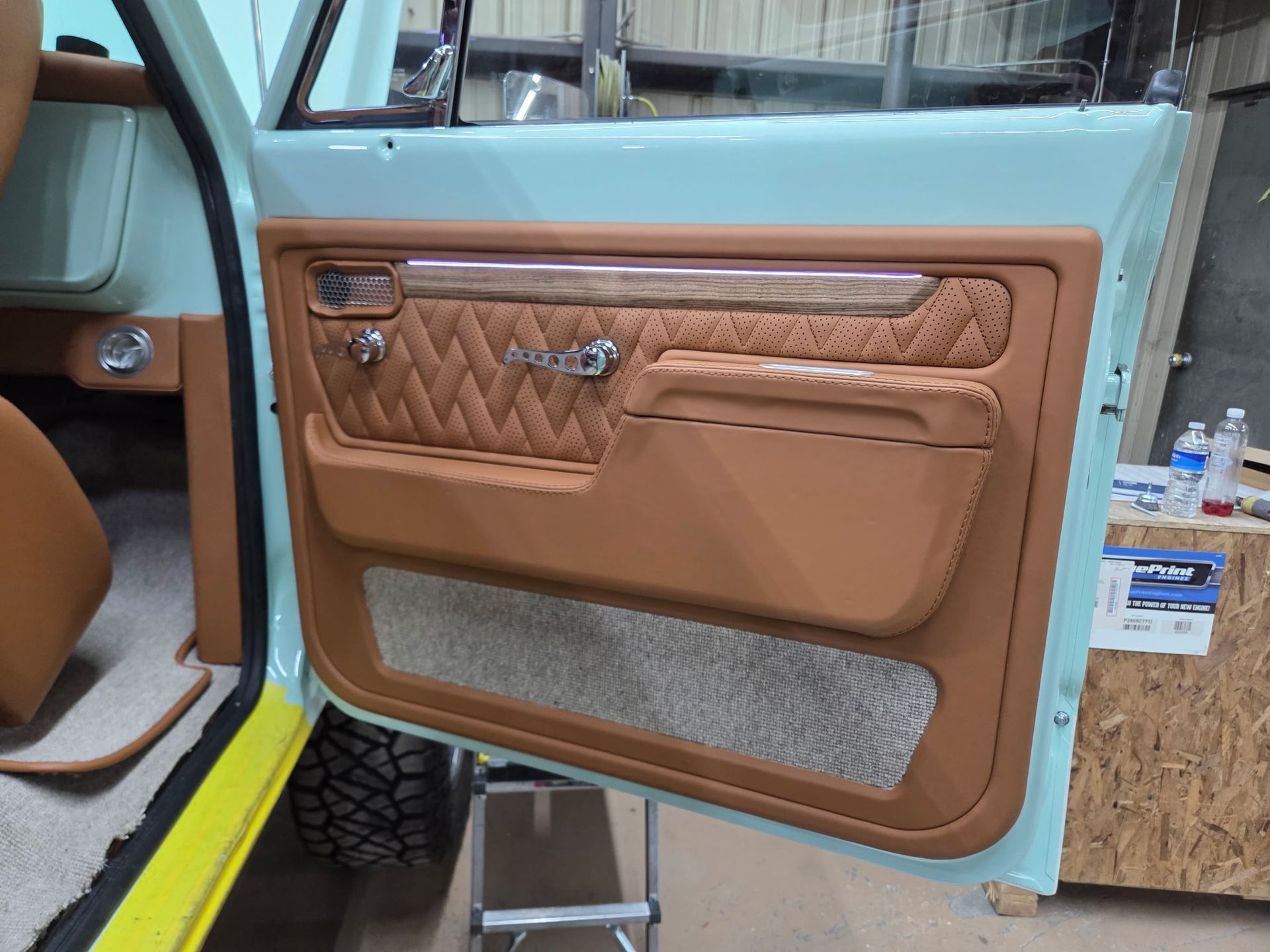 Interior car door with tan leather trim, diamond stitching, and aqua paint.