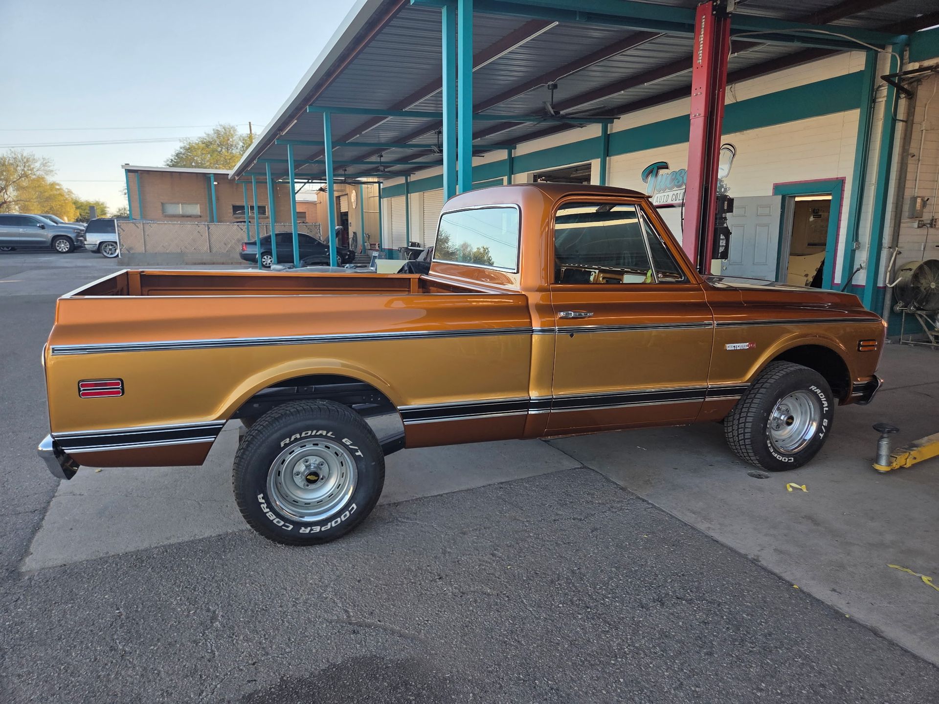 Classic two-tone orange and brown Chevy truck parked in front of a building with a blue awning.
