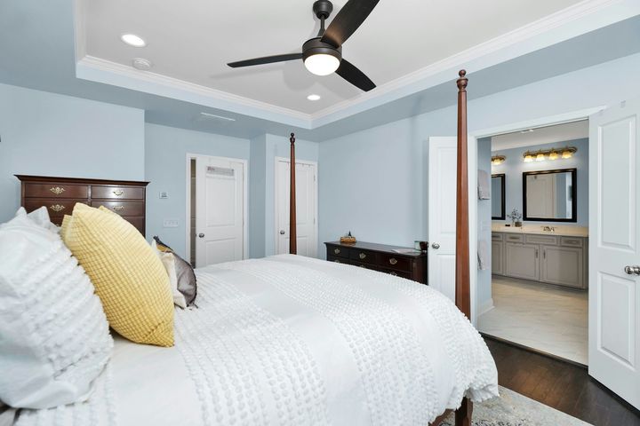 Two workers paint the facade of a white building, one standing on scaffolding and one on the ground near a yellow sign.