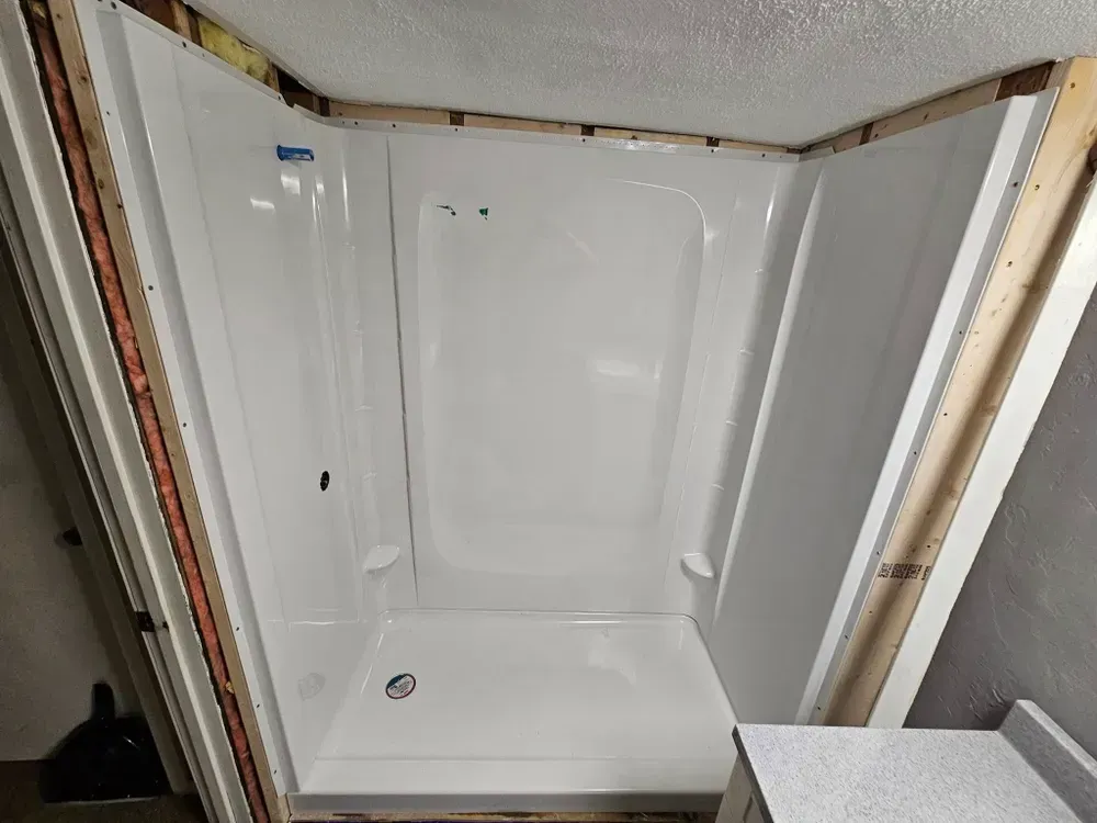 A white shower stall is being built in a bathroom.