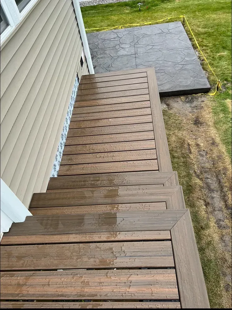 A wooden deck with stairs leading up to it next to a house.
