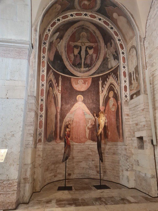 Una chiesa con un dipinto sul muro e due statue davanti.