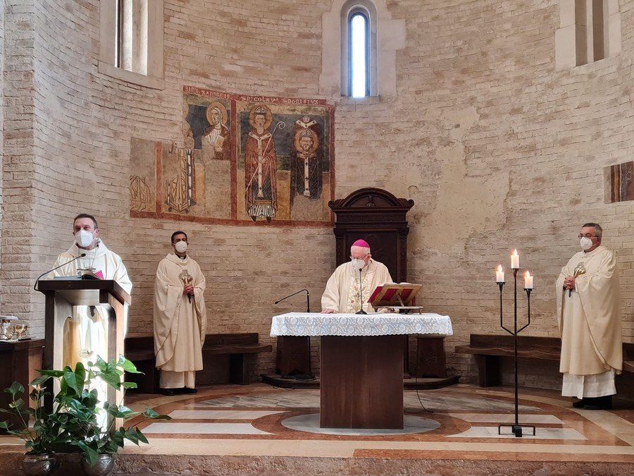 Un gruppo di preti che indossano maschere sono in piedi attorno a un altare in una chiesa.