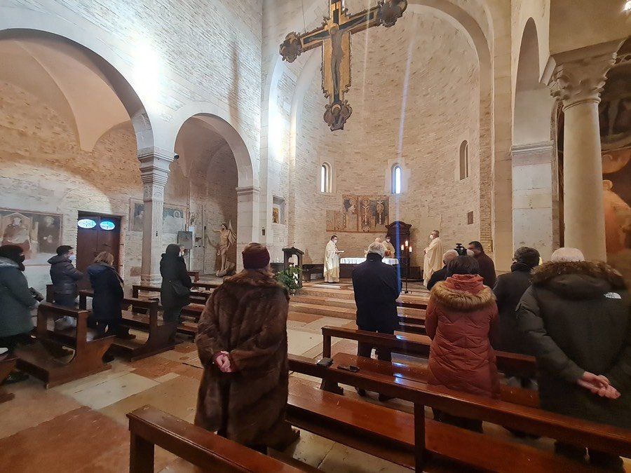 Un gruppo di persone è seduto in una chiesa con una croce appesa al soffitto.